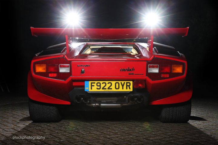 what's your favourite 'rear'? - Page 1 - Ferrari Classics - PistonHeads - The image captures a scene at dusk, featuring a striking red sports car resting on a brick-paved surface. The car's rear hatch and its spoiler lights are illuminated, adding a dramatic contrast to the dim background. The license plate, reading "F922 OYR," is visible, with the lights not only on the back but also on the side, casting a bright glow on the surrounding bricks. The car appears to be parked on a street with running water nearby, creating an atmospheric setting for the photograph.