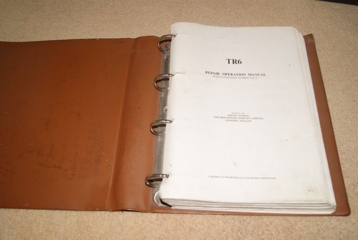 "free" to a good home - TR6 workshop manual - Page 1 - Triumph - PistonHeads - The image shows a notebook with a marbled cover that has a subtle mauve and grey swirl pattern. The notebook is slightly ajar, revealing a blank white page inside. The cover appears to be of a higher quality, perhaps designed for more discerning users. On the cover, there's a visible embossing of "TRE6" suggesting it might belong to a series or collection. The book is placed on a beige surface, which contrasts with the marbled pattern of the notebook, making the cover's details more noticeable.