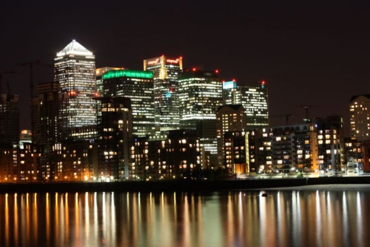 Night Place Town Pistonheads - The image captures a night time cityscape, bathed in the warm glow of streetlights and building illuminations. The skyline is dominated by tall skyscrapers, purposefully lit to stand tall against the night sky. A prominent feature of the cityscape is the natural element of a winding river that runs through the heart of the city, reflecting the city lights back in a mirror-like fashion. The city seems to be a thriving metropolis, with the lights indicating the vibrancy of nighttime city life. The presence of large signage on top of the buildings adds a decorative and commercial touch to the urban landscape.