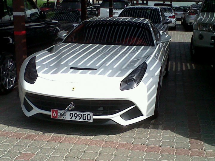 - Page 1 - Supercar General - PistonHeads - The image showcases a beautiful white Ferrari, its sleek form gleaming under the outdoor lighting. The car is sitting in a parking lot, adjacent to a tall support pole, indicating a maintained and modern urban area. There are other cars present in the background, but their details are not as distinct due to the distance. A license plate reading "69 99900" is prominently visible on the Ferrari, adding a personal touch to the vehicle. The overall scene captures a moment of quiet luxury amidst the everyday hustle of city life.