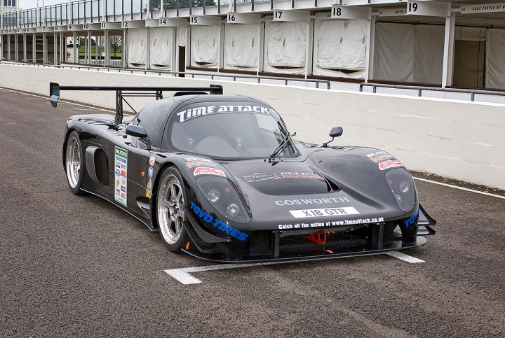 The Gallery - Ultima Photos Only Please - Page 11 - Ultima - PistonHeads - In the heart of a racetrack, a sleek black sports car commands attention. Its race number proclaims it in a competition, and the name "Time Attack" is prominently displayed on the windshield, a nod to its purpose. Two black spoilers stand out against the car's body, one above the other, aiding aerodynamics. The car bears various stickers and logos, some of which are blue and white. Each element in this image conveys the anticipation and excitement that surrounds professional auto racing.