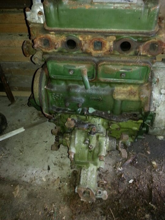 A close up of an old fire hydrant - Pistonheads - The image captures an industrial setting, where a large, rusty piece of machinery, specifically a green engine block with rivets, has been neglected. The engine block appears to be a 6-cylinder, named as such by white lettering among rust stains, suggesting this may be from a vehicle. The block is precariously mounted on a crumbling concrete floor, resting against a sturdy wooden wall. Around the block, various pieces of debris and other machinery are scattered, adding to the sense of disuse and decay. The overall scene conveys a sense of abandonment, with the rust and grime dominating the visual landscape.