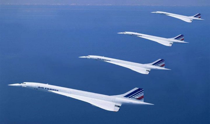 Post amazingly cool pictures of aircraft (Volume 2) - Page 202 - Boats, Planes & Trains - PistonHeads - The image displays four white supersonic jet aircraft against a clear blue sky. The planes are arranged in a straight line, maintaining a consistent altitude, suggesting they are in flight. Each plane has blue, white, and red stripes along its body, revealing the distinctive colors usually associated with the company operating them. The jet engine's high-speed exhaust can be seen above the planes, emphasizing their velocity.