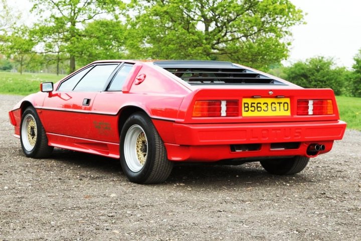 Late Pick Pistonheads - The image features a vibrant red, low-profile, sports car parked on a gravel surface. Trees are visible in the background, suggesting a natural or semi-wooded setting. The license plate indicates it's registered in England, with the text "Lorus GTO" visible. The car design appears modern and represents a Japanese manufacturer. The sun is out, casting a nice light on the car.