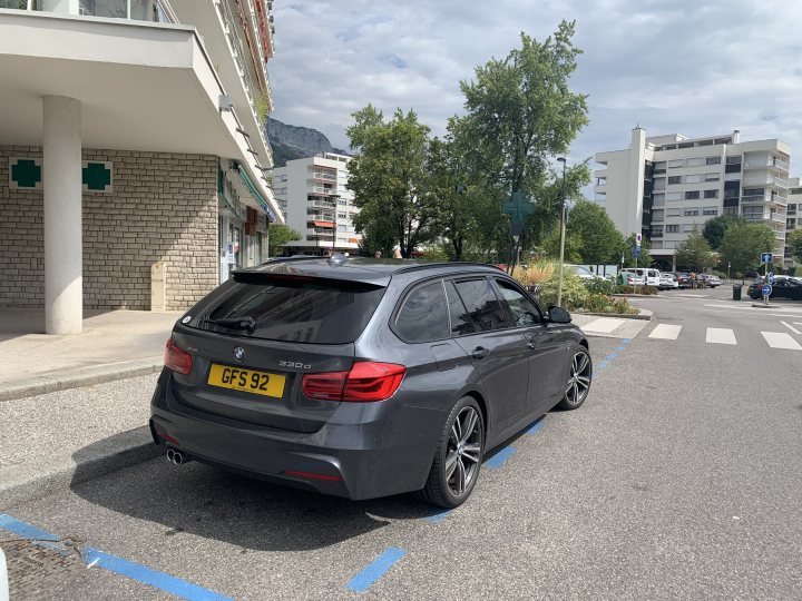 Unexpected family wagon - 2006 4.4V8 Vogue (going in blind!) - Page 41 - Readers' Cars - PistonHeads UK - The image shows a dark-colored BMW SUV parked in front of a building with an outdoor seating area. The car has a license plate that reads "0396". The vehicle is parked on the street, and the parking space is designated by blue markings. There are some greenery and trees in the vicinity, suggesting this location might be in an urban or suburban setting. The sky above indicates it could be a cloudy day.