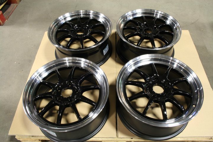 A bunch of different colored vases on a table - Pistonheads - The image shows black metal car rims against a light background, presumably in a factory or garage setting. Highlighting the interior of the rims, the photo emphasizes the hexagonal spoke design characteristic of wheel hubs. There are four rims arranged in a block pattern. Each rim is smooth and appears new, suggesting the image might have been taken during manufacturing or inspection. The setting seems industrial, characterized by grey flooring, a concrete surface, and industrial workers visible in the background.