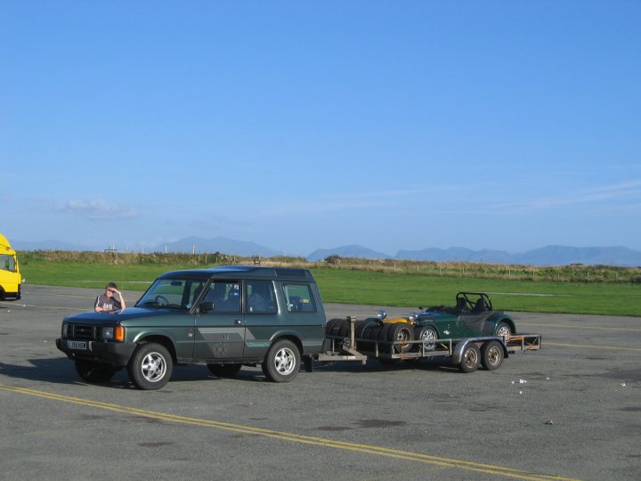 Show us your Daily driver, and Weekend Toy(s)!!! - Page 3 - Readers' Cars - PistonHeads - In the vast expanse of the clear blue sky, a solitary SUV is parked on a concrete lot, its cargo hold filled with various items. A bright yellow truck, possibly being used as a watering truck, stands nearby. Beyond the lot, a stark contrast with the pristine white of theRV. The terrain is flat, with a grassy field stretching out to meet the horizon. The sky above is a serene blue, dotted with a handful of scattered clouds.