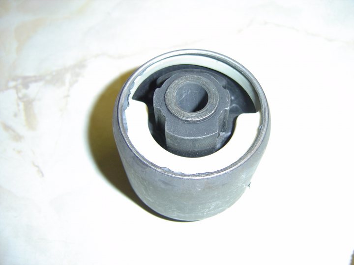 Pistonheads - The image shows a close-up of a black cylindrical object with a central hole, possibly a mechanical seal or a connector of some sort, set against a white marble surface. The object's ends are bitruely formed but the main purpose seems to be acting as a sealing mechanism, indicated by the raised edges near the hole. The image is taken from a side view, emphasizing the object's cylindrical shape and length. The marble surface beneath provides a studied contrast to the object's dark color.