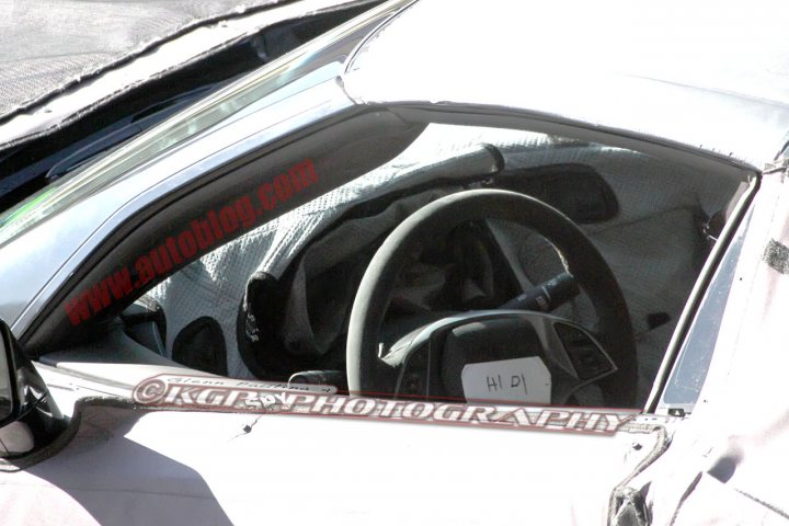 C7  Bucket seats and glimpse of the new steering wheel - Page 1 - Corvettes - PistonHeads - The image is a photograph of the interior of a car, focusing on the driver's side. The dashboard is visible and features the branding "AUDI" and an "HDI" label, along with the website address "www.audi.com." A portion of the steering wheel is shown, exposing the equipment behind it. The lower part of the windshield displays the name "CROSSPHOTOGRAPHY." The image appears to be a rear view showing part of the windshield and the interior of the car, possibly taken from an adjacent vehicle, and may include watermarks from a photography business.