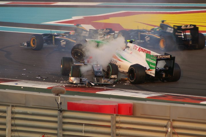 Recommended grandstand for Abu Dhabi grand prix? - Page 1 - Middle East - PistonHeads - The image captures an intense scene at a Formula One race track. Four race cars have collided in front of the grandstand, with visible damage and debris scattered across the track. Smoke is rising from the wreckage, signifying the incredible impact and possible fire. Two of the cars involved in the crash are predominantly black and white, while the third car has green and red livery. The fourth car, mostly white and green, appears to have escaped the accident relatively unscathed. Spectators are likely to be surprised and shocked by this incident mid-race.