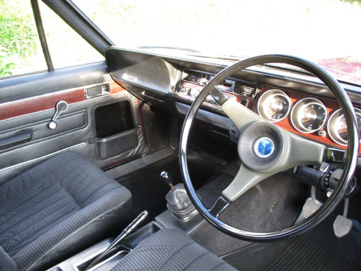 Hillman Avenger GLS Restoration - Page 1 - Readers' Cars - PistonHeads - The image captures a classic old-style car interior. Dominating the scene is a black leather steering wheel, a testament to the car's age. The viewer's perspective is from the passenger's seat, providing a comprehensive view of the interior. The dashboard, featuring chrome details and circular gauges, dominates the upper portion of the view. The gear shift is on the left side of the steering wheel, a typical setup in many classic cars. The colors and design elements of the car suggest it's a piece of automotive history.