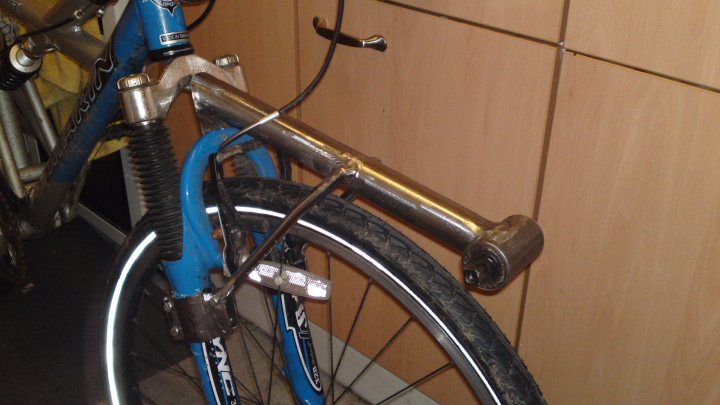 Pistonheads - The image captures a close-up view of a bicycle parked against a wooden wall, showcasing parts of its frame. The bicycle features a vibrant blue frame that extends prominently into the frame. Attached to the frame is a lock, a crucial component for securing the bike while it's unattended. The lock's position, just above the silver pedal and handlebars, suggests a heightened concern for security. Despite the bike being stationary, the image encapsulates a sense of readiness and mobility.