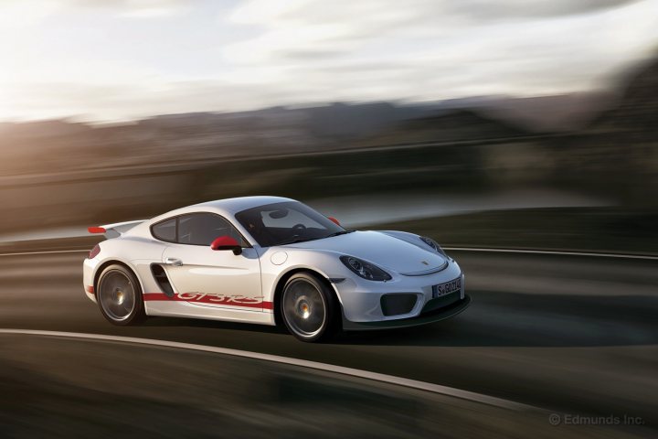 boxster / cayman GTS - Page 1 - Boxster/Cayman - PistonHeads - The image features a sportscar on a curvy road. The car is a high-performance model with a sleek design and red accents. It is moving at speed, indicated by the blurred effect on the background and road, which suggests dynamic motion. The weather appears to be sunny, suggesting daytime, and the car is the main focus of the image, taking up a significant portion of the frame. There is a signature watermark present at the bottom of the image.