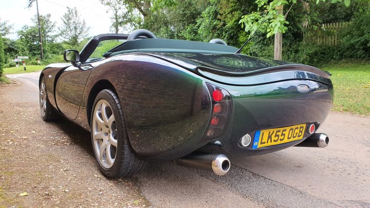 A black car parked in a parking lot - Pistonheads - The image shows a sleek, green two-door convertible sports car parked on the side of a road. It has a unique design with a large rear wing, which is a characteristic feature of high-performance cars. The vehicle appears to be in good condition and is equipped with a license plate. There's also a small, round emblem on the hood, but it's not clear what brand it represents. The car stands out against the natural backdrop that suggests a rural or suburban setting.