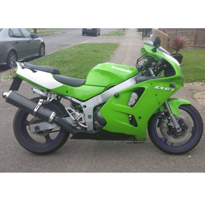 A red motorcycle parked on the side of a road - Pistonheads - This image captures a Kawasaki ZX-R racing motorcycle parked on a street. The motorcycle is a vibrant green, striking against the gray concrete of the road. Its black seat contrasts with the green body, adding to its aggressive aesthetic. In the background, there's a black car parked nearby, and a potted plant adds a touch of greenery to the otherwise urban scene. The motorcycle's position and angle suggest it's ready for action.