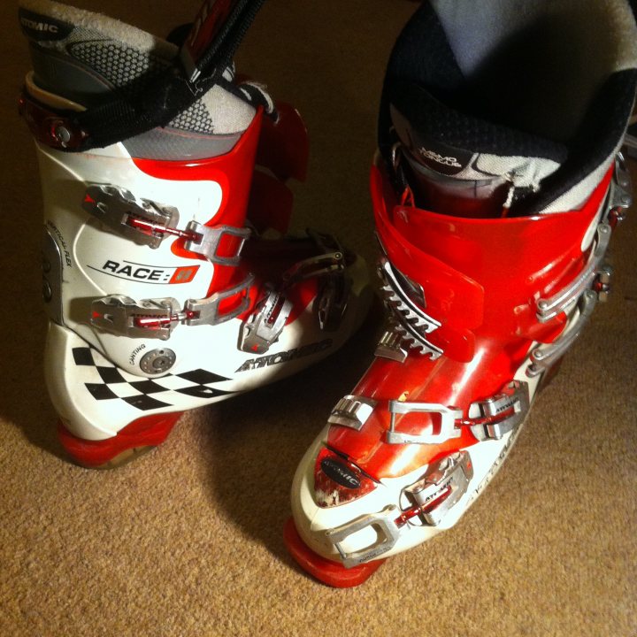 Ski / Snowboard 2014 - Show us your gear - Page 1 - Sports - PistonHeads - The image displays a pair of red and white snowboarding boots positioned on a carpeted floor. The boots have a distinctive checkered pattern, which is typical for brand recognition. The design of the boots suggests they are secured to the snowboard with a three-pronged system at the toe area. The buckles and straps indicate that they are adjustable and designed for protection and comfort. The boots appear to be well-used, as indicated by the wear and smell associated with equipment used for winter sports.