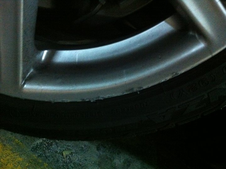 Front Buy Pistonheads Vantage Wheel Roadster - The image shows a close-up view of a vehicle's wheel, focusing on the metallic rim. The wheel is dark in color and appears to be made of a metal alloy. There is a noticeable indentation in the wheel rim, suggesting damage or wear. This detail draws the eye, and it's difficult to determine if it's a part of the design or an imperfection. The specific model or type of vehicle is not discernible from the image. The photo seems to be taken from below, looking upwards towards the wheel.