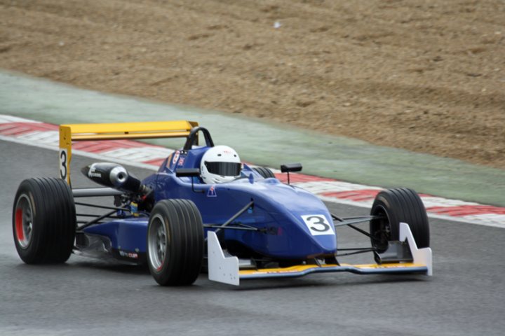 Pistonheads - The image showcases a professional race car in full throttle on a track. The car, painted in a striking shade of blue with a yellow roof, is racing around a curve on the track. It has the number "3" emblazoned on its side, and the driver is wearing a white helmet, indicating the intensity of the competition. In the background, the track extends into the distance, setting the scene for a high-speed world of motorsports.