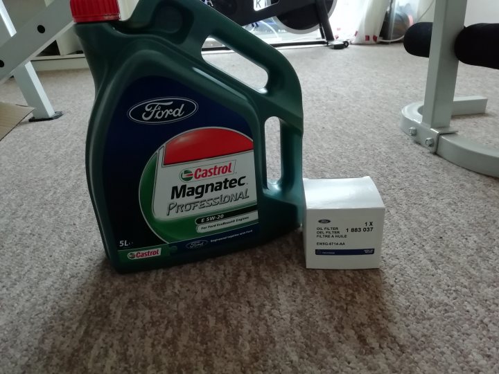 Fiesta St 180 - Page 5 - Readers' Cars - PistonHeads - The image shows a garage floor setting where a motorcycle is present. There are two bottles of motor oil, one on the left labeled "Castrol Magnetec" and the other on the right, which is a smaller bottle also from Castrol. Between these bottles, there's a box that seems to contain a product related to the motorcycle maintenance. The floor appears clean, and in the background, you can see a part of an exercise machine or treadmill, suggesting this might be an indoor space where both vehicle maintenance and fitness activities take place.