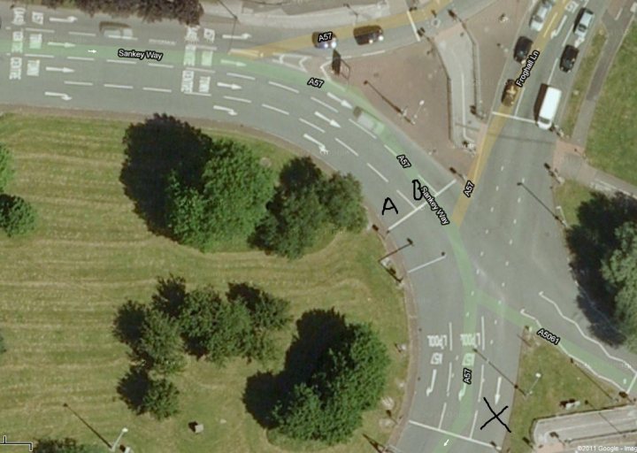 Roundabout Pistonheads Question - The image presents a colorful, aerial view of an urban intersection, marked by distinct paths labeled with letters A and B. The scene is a blend of greenery and concrete, with a variety of traffic and labeled signs. The road network is interconnected with green lines indicating paths or bike lanes, providing a sense of the intersection's complexity. Vehicles and trucks of different colors and models are scattered throughout the scene, adding a sense of life to the urban landscape. The image captures the essence of a busy, developing area.