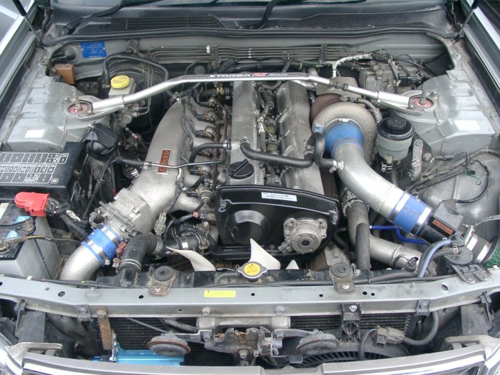 Pistonheads Street Sleeper - The image depicts a detailed view of the undercarriage of a car engine. The photo provides a comprehensive look at the engine, showcasing the complex assembly and mechanical components. The engine is encircled by various hoses and tubes, indicating the intricate network that powers the vehicle. This image is likely taken from the perspective of the car bonnet or after removing the bonnet.