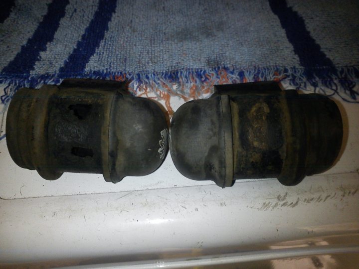 A close up of a train on a train track - Pistonheads - The image presents a pair of old, dirty car bumper covers resting on top of a chipped white floor. These black components are symmetrically positioned next to each other, all showing signs of wear and tear. They seem to be placed in front of a colorful striped carpet, creating a stark contrast between the old automotive parts and the vibrant patterned rug.