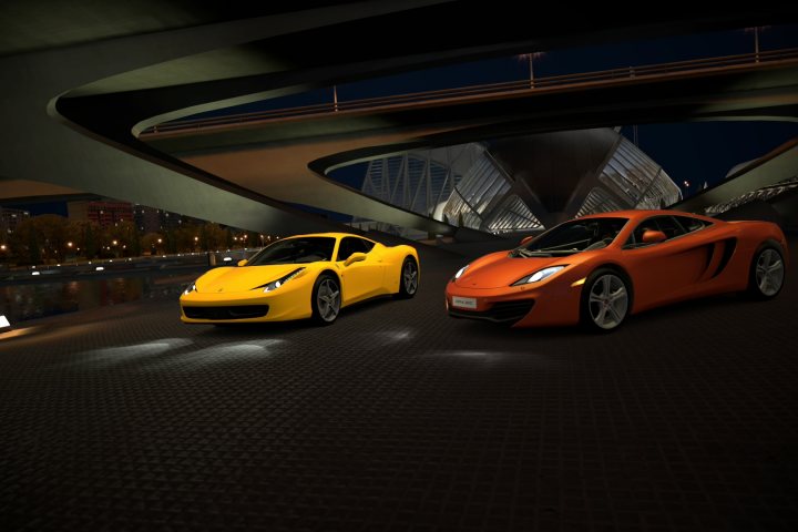 Gran Turismo 6 picture thread - Page 3 - Video Games - PistonHeads - The image showcases two sports cars with a futuristic design, spotlighted against the backdrop of a modern cityscape. The yellow car and the orange car flank the viewer, each exhibiting unique characteristics that include intricate headlights and sleek aerodynamics. They are set on a 3D rendered street, suggesting they are in a bustling urban environment. A captivating night scene frames the image, accentuating the vibrant colors and glossy reflections of the cars, adding a sense of dynamic motion to the scene.