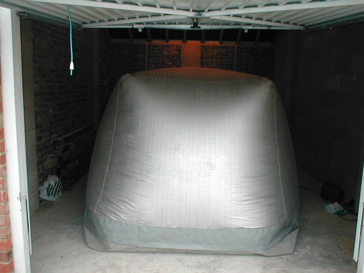 Carcoons - are they any good? - Page 1 - Classic Cars and Yesterday's Heroes - PistonHeads - This image showcases a closed garage workshop with a large wraparound cover. The cover appears to be made of a reflective and shiny material, possibly a tarp or a similar type of material, and it is made to completely encapsulate the space within the garage. The cover gives the impression of modern technology within the garage, suggesting a cutting-edge space for some sort of security or automotive-related work. No other specific items or people are visible; the main focus is on the wrapping material and the covered garage area. The lighting in the photograph highlights the reflective surface of the cover, creating spots of light and shadow within the garage. Despite the absence of people or objects, the image conveys a sense of industrial design and functionality.