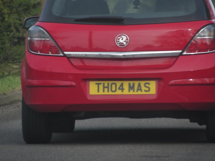 Real Good Number Plates : Vol 4 - Page 315 - General Gassing - PistonHeads - This image captures the rear view of a vibrant red car that's stopped on a street, possibly at an intersection or a traffic signal. The car is adorned with a registration plate that reads "TH04 MAS". On the trunk, there's a badge that adds to the car's distinctive appearance. The background reveals a serene suburban setting with houses and trees. The scene evokes a sense of everyday life and the journey that the car and its passengers might be embarking on.