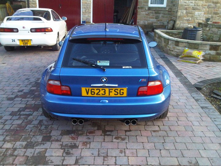 Coupe Honda Pistonheads Bmw Itr - The image depicts a vibrant scene set in a brick driveway. Dominating the foreground is a sleek blue BMW, its license plate standing out as it reads "V623 FSG". The BMW is positioned such that it partially blocks the view of a white car parked behind it. In the background, a solitary figure can be spotted, adding a touch of human presence to the otherwise mechanical setting. Softly bathed in the light of a nearby window, this individual seems to be busily engaged in some task, perhaps related to the storage shed situated on the right side of the frame. The entire scene paints a lively picture of everyday life, with its blend of nature's elements and man-made objects.