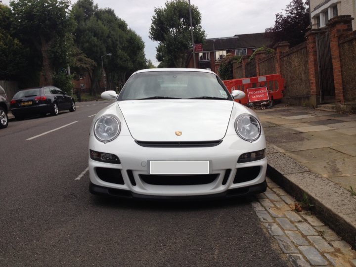 Picked up my 997.1 GT3 the other day :)  - Page 1 - 911/Carrera GT - PistonHeads - The image features a white Porsche parked on a city street. It's positioned near a red construction barrier. The Porsche is parked on the left side of the road. The background of the image shows a residential street with other parked cars.