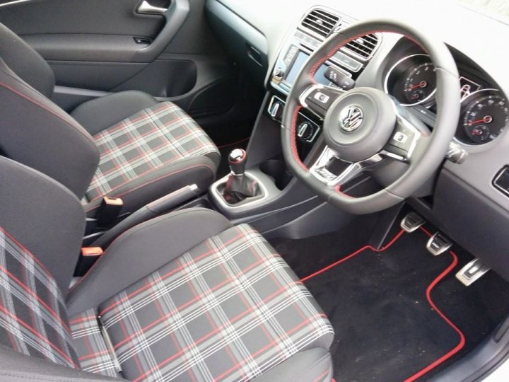 A black and white photo of a man in a car - Pistonheads - The image shows the interior of a car from the perspective of the front passenger seat. The front seat features a design with gray fabric and a colorful plaid pattern. A bottle of water bottle is placed in the cup holder. The steering wheel appears to be in the driver's place, and the dashboard shows a cluster of the vehicle's control instruments, including speedometer and fuel gauge, among others. The overall style of the image is realistic, likely used for selling a vehicle or showcasing interior design.