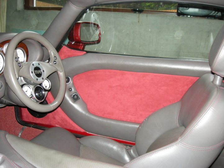 Rare Pistonheads Golf - The image showcases the inside of a compact Audi sports car. The interior of the car is predominantly in gray, with the driver's side featuring a steering wheel equipped with a range of buttons and knobs. Red accents decorate the dashboard and footwell area, adding a pop of color to the otherwise neutral palette. The car is well-maintained, with a clean exterior and few visible scratches. The interior appears to be unused, as it looks pristine and unoccupied.