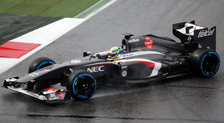 A motorcycle parked on the side of a road - Pistonheads - The image depicts a Formula 1 car in mid-motion on a racetrack during a race. The car, predominantly sleek and black in color, has the number 8 on the side and sports a stripe pattern of red, white, and gray. It also has logos and text on the body, including the "NEC" name prominently displayed, suggesting it's a French company's sponsored vehicle. The driver's helmet, visible in the cockpit, matches the car's color scheme, and he is focused on the road ahead, which curves to the left in the background. The aesthetic of the image captures the speed and intensity of a Formula 1 race.