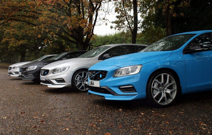 RE: Volvo V60 Polestar: Spotted - Page 2 - General Gassing - PistonHeads - The image showcases a group of four cars parked side by side on a gravel surface. The cars are positioned next to each other on a sandy beach, which is sheltered by trees. The sky overhead is overcast, suggesting either an early morning or late afternoon timeframe. The vehicles are modern in design, exhibiting aerodynamic bodywork and alloy wheels.