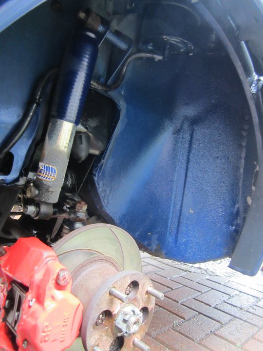 A close up of a motorcycle with a helmet on it - Pistonheads - The image shows a close-up of a vehicle's undercarriage, specifically focusing on the area which appears to be a disc brake assembly. The brake pad is visible, with a red color suggesting it may be worn and might need to be replaced. Attached to this part of the vehicle is a cylindrical object, possibly a part of the suspension or steering system, which has a variety of components like nuts, bolts, and possibly an air conditioning connection or a hydraulic mechanism. The perspective is from above the vulnerable bottom side of the vehicle.