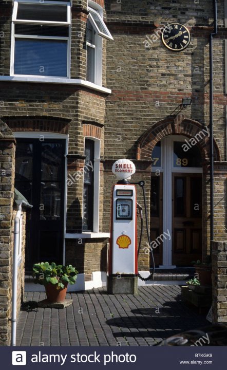 Toshiba battery 6 minute charge 200 mile range soon... - Page 5 - General Gassing - PistonHeads - The image captures a quaint street scene featuring a stationary gas pump, specifically a Shell petrol pump, located in front of a brick building with a sign saying "89". The pump is mounted to the side of the road, adjacent to a tarmac-surfaced sidewalk. The building, characterized by its brick architecture and arched doorway, serves as a backdrop to the street scene. A potted plant can be spotted on the sidewalk, adding a touch of greenery to the urban setting. The image conveys a sense of comfort and ubiquity in the everyday sights of city life.