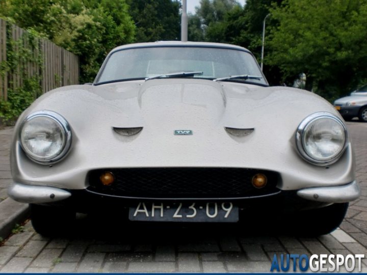 Early TVR Pictures - Page 81 - Classics - PistonHeads - The image shows a classic silver coupe parked on a residential street. The car's pointed grill and narrow headlights are characteristic of its vintage design. The license plate is clearly visible and has the registration number "AH23-09". The setting is tranquil with trees and a well-maintained sidewalk in the background. On the lower right corner, there's a watermark that reads "AUTO GESPOT", suggesting that the image is from an automobile listing or website.