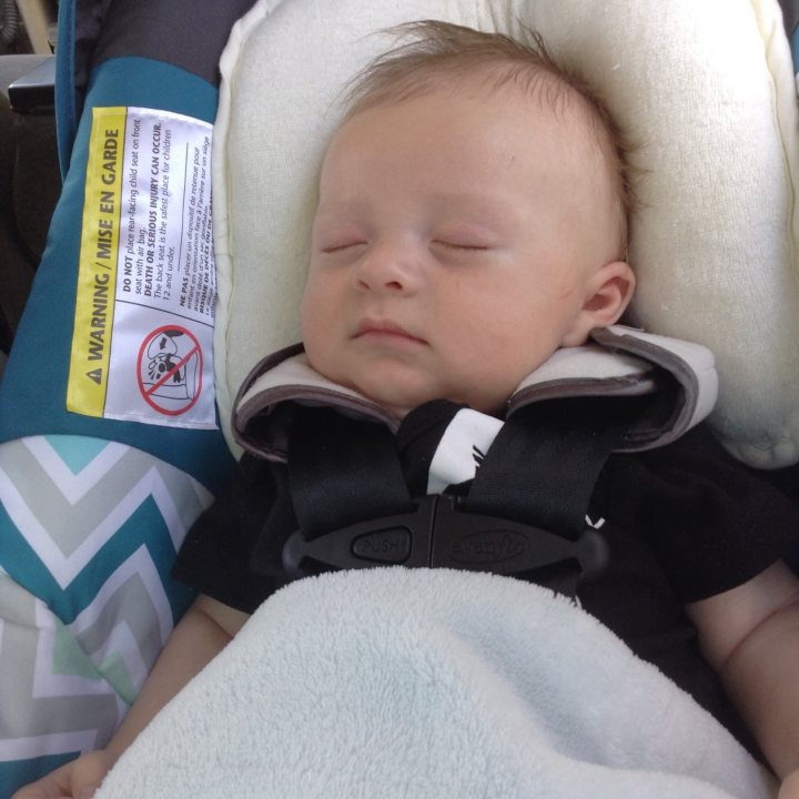 A little boy sitting in a chair with a tooth brush - The image captures a serene moment in a car, where a young baby is peacefully sleeping in their carseat. The baby, who appears to be a girl, is swaddled in a white blanket and is securely fastened in her black car seat. The car seat features a harness mechanism, ensuring the baby's safety. Across the right armrest, there's a white safety cover providing extra protection. There is also a car seat instruction tag placed near the car seat, a reminder of the importance of child safety during rides.