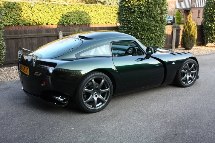 A car with a surfboard on top of it - Pistonheads - This image captures a striking sports car, painted in a glossy black. The car is parked on a gray driveway, right in front of a well-manicured hedge. The vehicle features large alloy wheels and an air intake vents, indicative of its sporty nature. The required license plate is prominently displayed at the back, adhering to the local regulations. The overall scene exudes a sense of sophistication and speed.