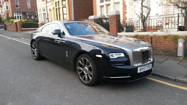 Spotted In South Wales (Vol 3) - Page 213 - South Wales - PistonHeads - The image shows a luxury vehicle, specifically a Bentley, parked on the side of a street. The car has a sleek design with chrome details and alloy wheels. It's positioned next to a sidewalk lined with houses in the background. The license plate is clearly visible on the back of the vehicle, though not legible in this description. The photo seems to have been taken during daylight under clear conditions, and it does not contain any text or additional information about the location or time.