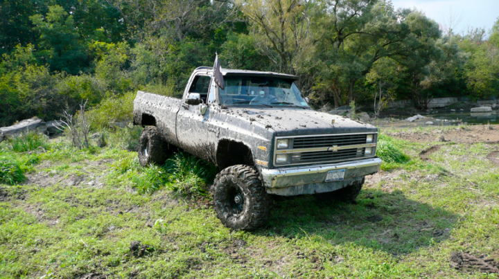 Towing/recovery with a Defender... - Page 1 - Off Road - PistonHeads - The image features a dirty, white Chevrolet truck parked in a grassy area. The truck appears to be an older model, given its robust and somewhat rugged design. The vehicle is parked on grass, with its tires partially covered in mud, suggesting it may have navigated through an off-road area with muddy terrain.

In the background, there are trees, adding a natural element to the scene. The truck appears to be quite large, occupying a significant portion of the image. The setting seems peaceful, with no signs of immediate activity or interaction. There are no visible texts or numbers on the truck, and the overall condition of the vehicle suggests it may have been used extensively or in challenging conditions.