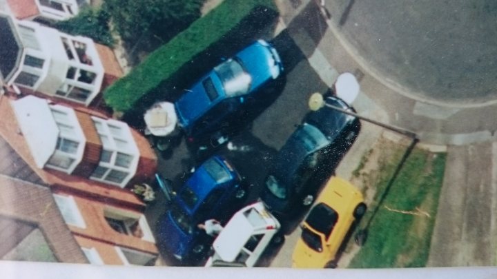 Help identify this car...  - Page 1 - General Gassing - PistonHeads - The image captures an unusual interaction of domestic two-story brick houses with blue vehicles parked within a residential neighborhood. The blue cars are confined by an astroturf snow fence, its yellow fence post standing out against the green grass of the lawn. To the left of the image, one blue car is parked on the back lawn of a three-story building with a red roof. The vibrant blue of the cars matches the refreshment of a new, glossy paint job.