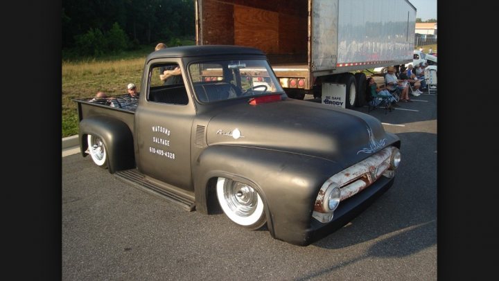 Pictures of decently Modified cars [Vol. 2] - Page 172 - General Gassing - PistonHeads - The image shows a vintage black pickup truck that appears to have a classic design. The truck displays a large, bold text reading " ain't no name on the side of this truck" on its side, and there is also some Rust on its side and hood, giving it an old and possibly well-used look. It is parked in a dirt lot next to a semi-truck. Behind the semi-truck, there are several spectators lined up, suggesting that this could be a car show or similar event.