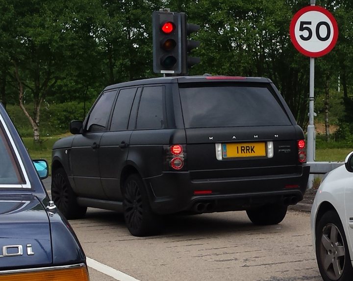 Real Good Number Plates : Vol 4 - Page 347 - General Gassing - PistonHeads - The image shows a black Range Rover car driving on a street. The car is seen from the side and is positioned in front of a speed limit sign which displays the number 50. The road appears to be a two-lane street, and there is another vehicle visible in the background, indicating that there is traffic. The car has a distinctive black color and its size and shape are characteristic of an SUV.