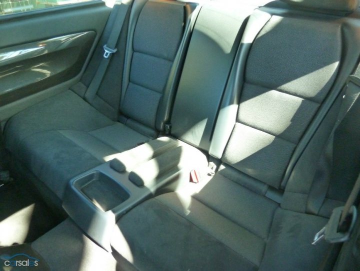 A car is parked on the side of the road - Pistonheads - The image showcases the spacious rear seat area of a car interior. The seats, covered with a gray fabric, are designed with two headrests and a center console. The straps and buckle of the seatbelt are clearly visible, emphasizing safety features. The car's seating arrangement appears to be designed for comfort and functionality.