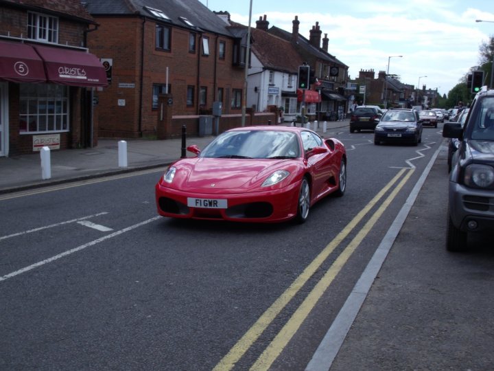 A red car is driving down the street - Pistonheads
