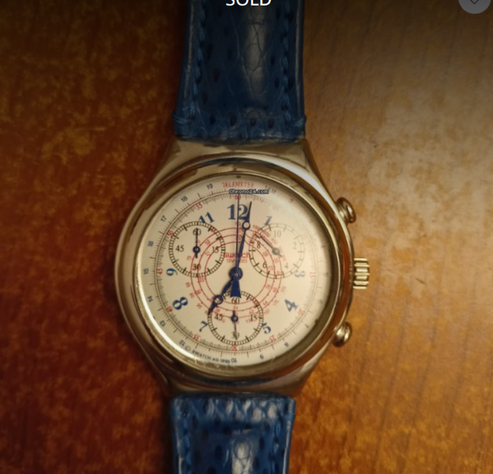 The image shows a close-up of a watch with a white face and black numerals. The watch is encased in a silver frame, and the band appears to be blue. On the wrist of the watch, there's a blue leather strap. The image has a watermark that reads "SOLD" across the top, indicating that the item has been purchased or is no longer available for purchase. There is also a small price tag icon in the corner of the image. The background is not clearly visible due to the focus on the watch.