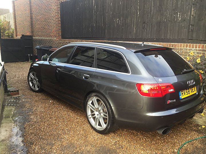 Audi RS / S / R8 picture thread! - Page 1 - Audi, VW, Seat & Skoda - PistonHeads - The image shows a black Audi estate parked in a driveway. The car is positioned sideways to the viewer, allowing a clear view of its side profile. It features multiple doors, indicative of its station wagon design, which is common for families and small businesses. The Audi logo is visible on the trunk of the vehicle. The background includes a red brick wall, adding a warm contrast to the cool, modern look of the car. The driveway itself is composed of gravel, suggesting an outdoor residential area.