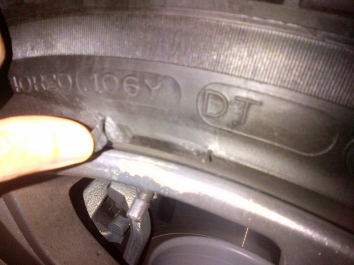 Cut in sidewall if tyre - is it still OK? - Page 1 - General Gassing - PistonHeads - The image shows a close-up view of a vehicle's wheel, with a focus on the hubcap. On the hubcap, there is text that reads "DJ CONSTRUCTION INC" and "4L TRUCK," indicating the manufacturer and the purpose of the tire. A person's hand is visible in the frame, holding onto the wheel to either remove or attach the hubcap. The side of the hubcap is flattened, suggesting it was recently used or taken off from a tire.